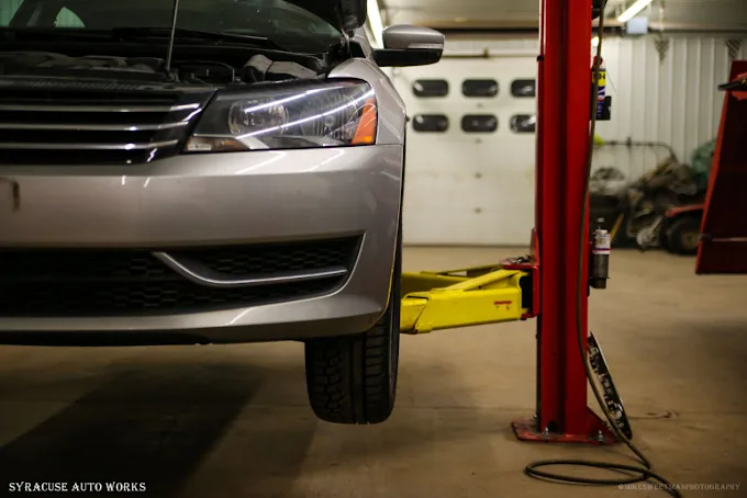 A sedan raised on a two-post lift inside the shop.